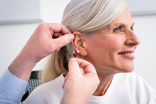 Ältere Frau erhält ein modernes Hörgerät zur Verbesserung des Hörvermögens eingesetzt.